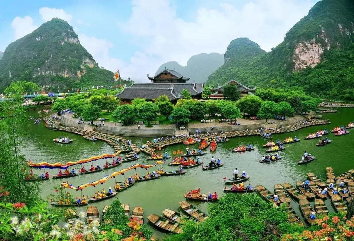 Rowboats fill a lake beside a temple complex at Trang An, surrounded by limestone karsts in Ninh Binh.