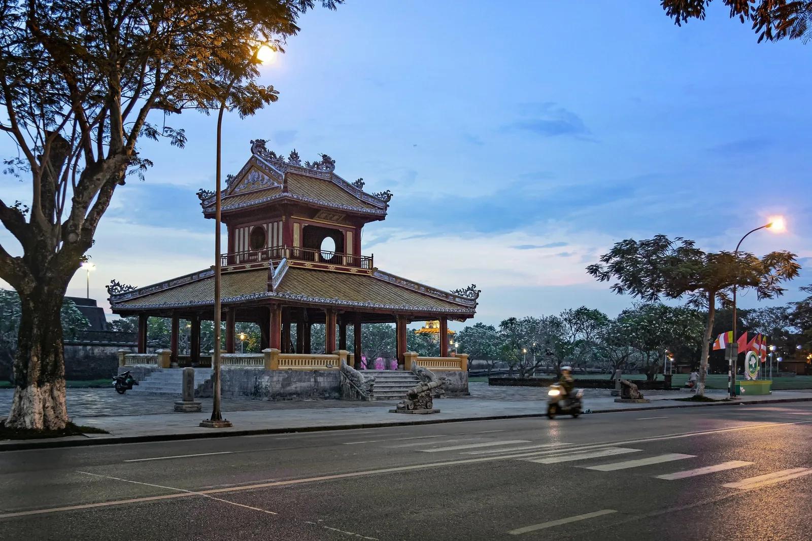 Phu Van Lau pavilion glows at dusk beside a quiet street in Hue's imperial city.