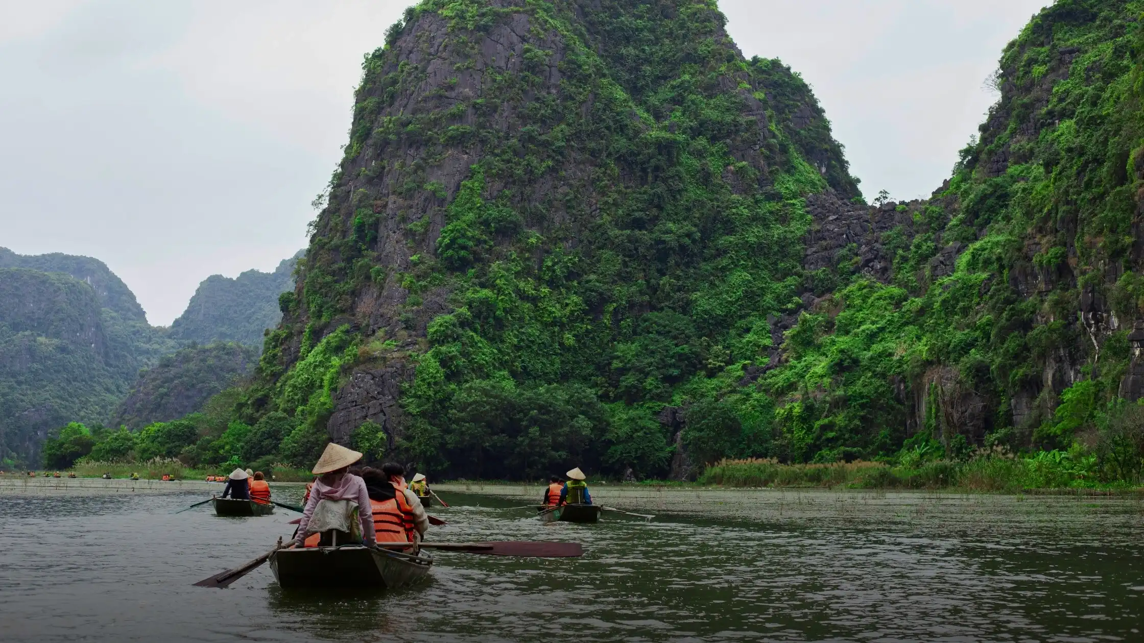 Rowboat passing between karst peaks on a river in Ninh Binh