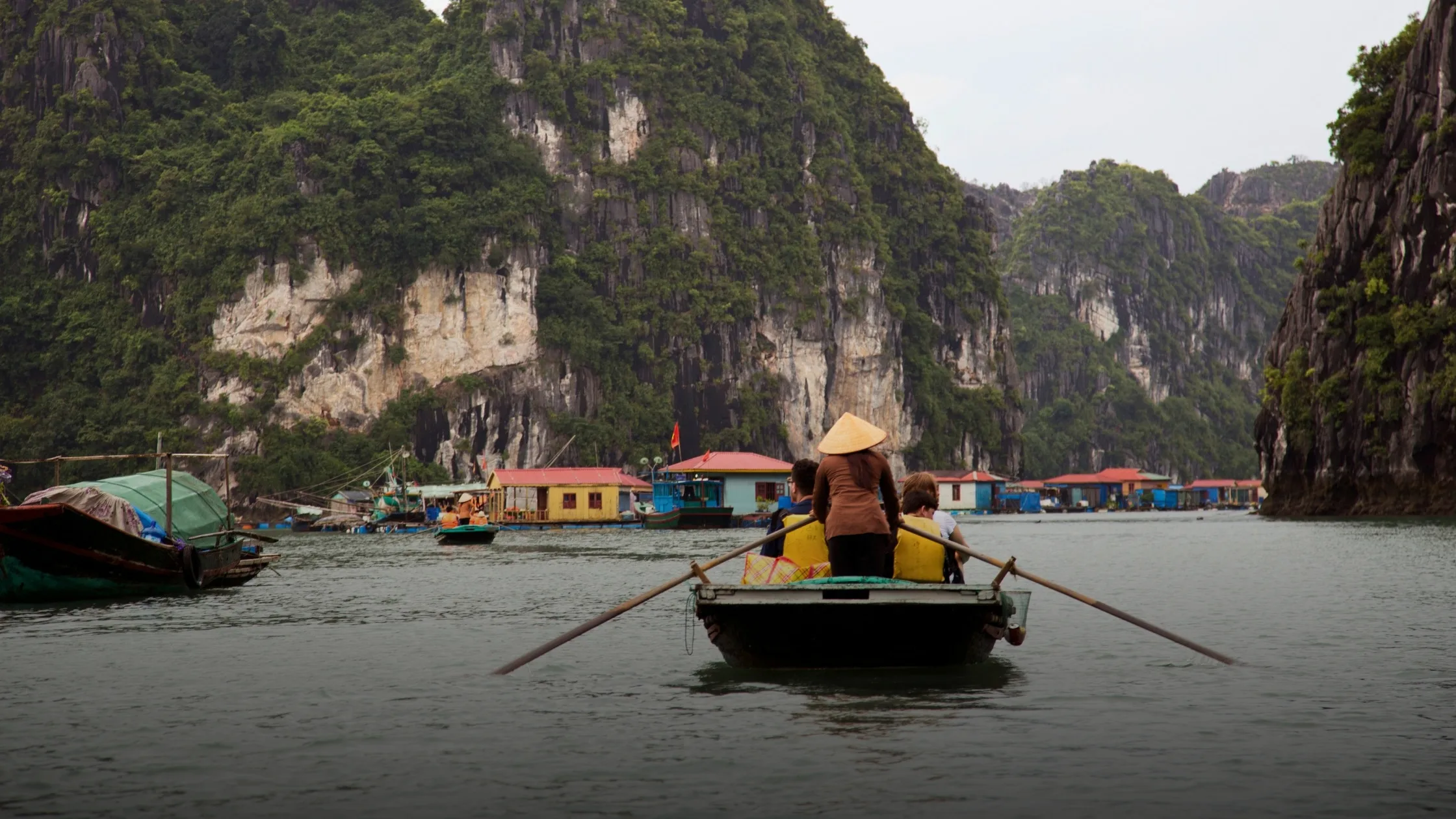 Wooden junk boat sailing between limestone islands in Ha Long Bay