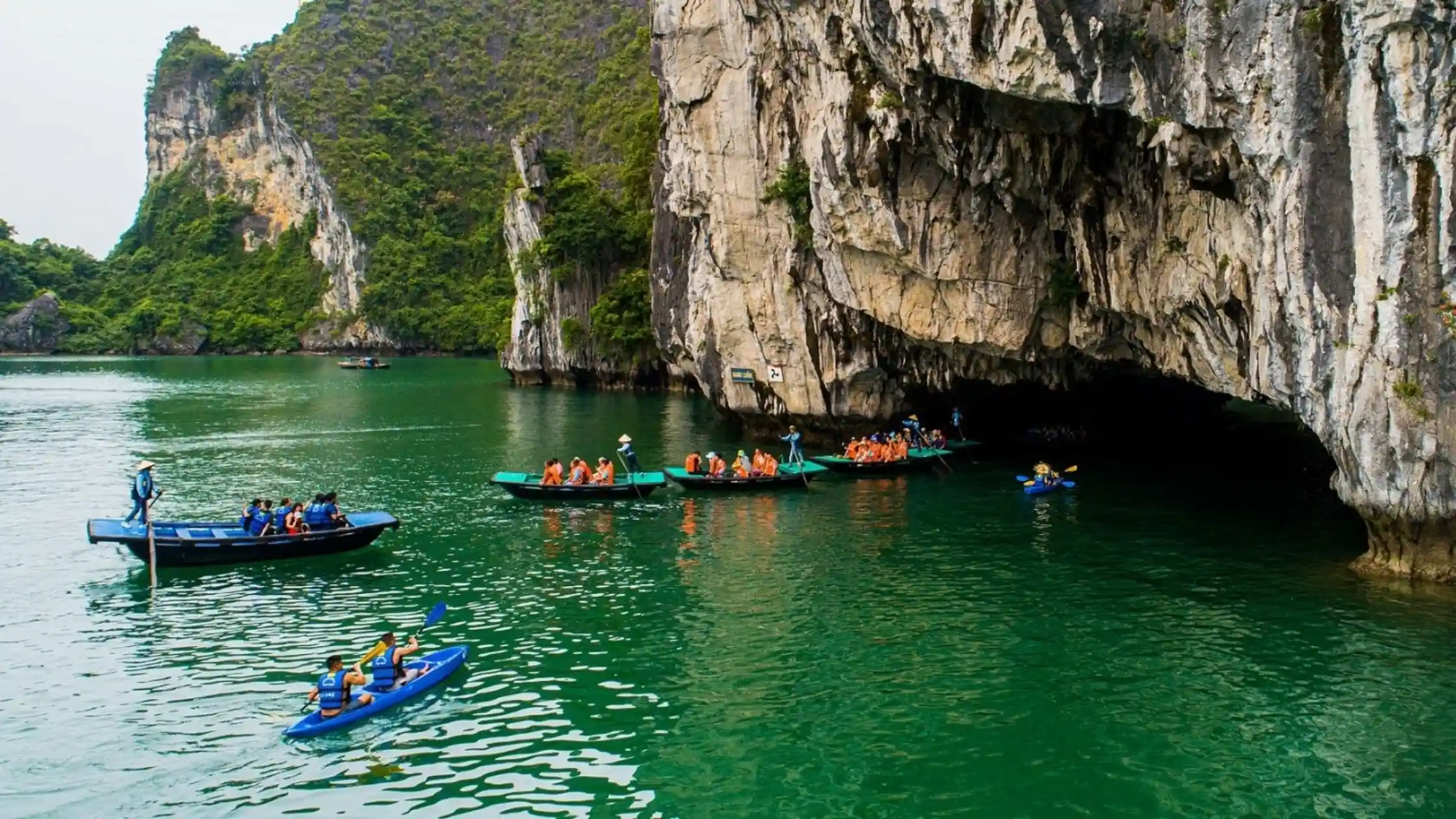 Kayaks beside a cruise boat in Bai Tu Long Bay