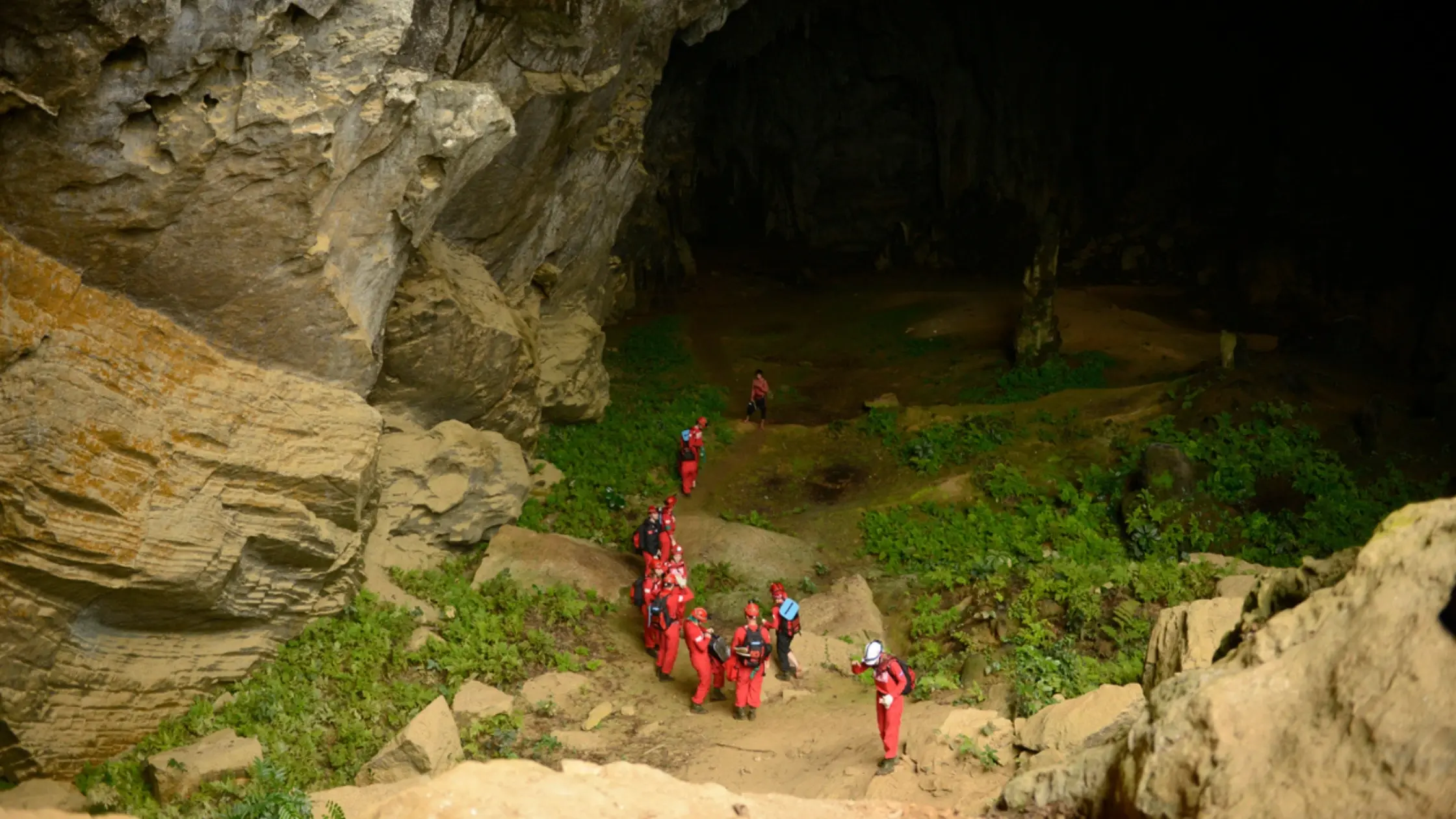 Group with headlamps entering a river cave in the Tu Lan system