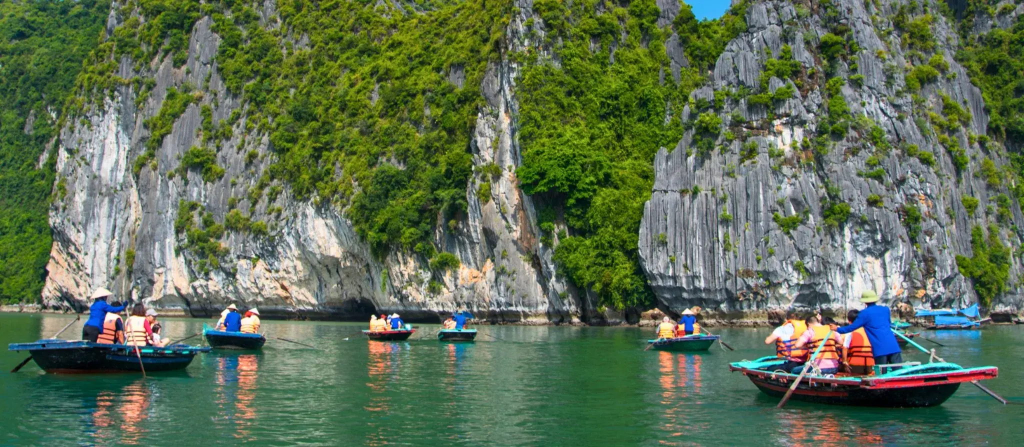 Small beach and calm water between limestone cliffs in Ha Long Bay