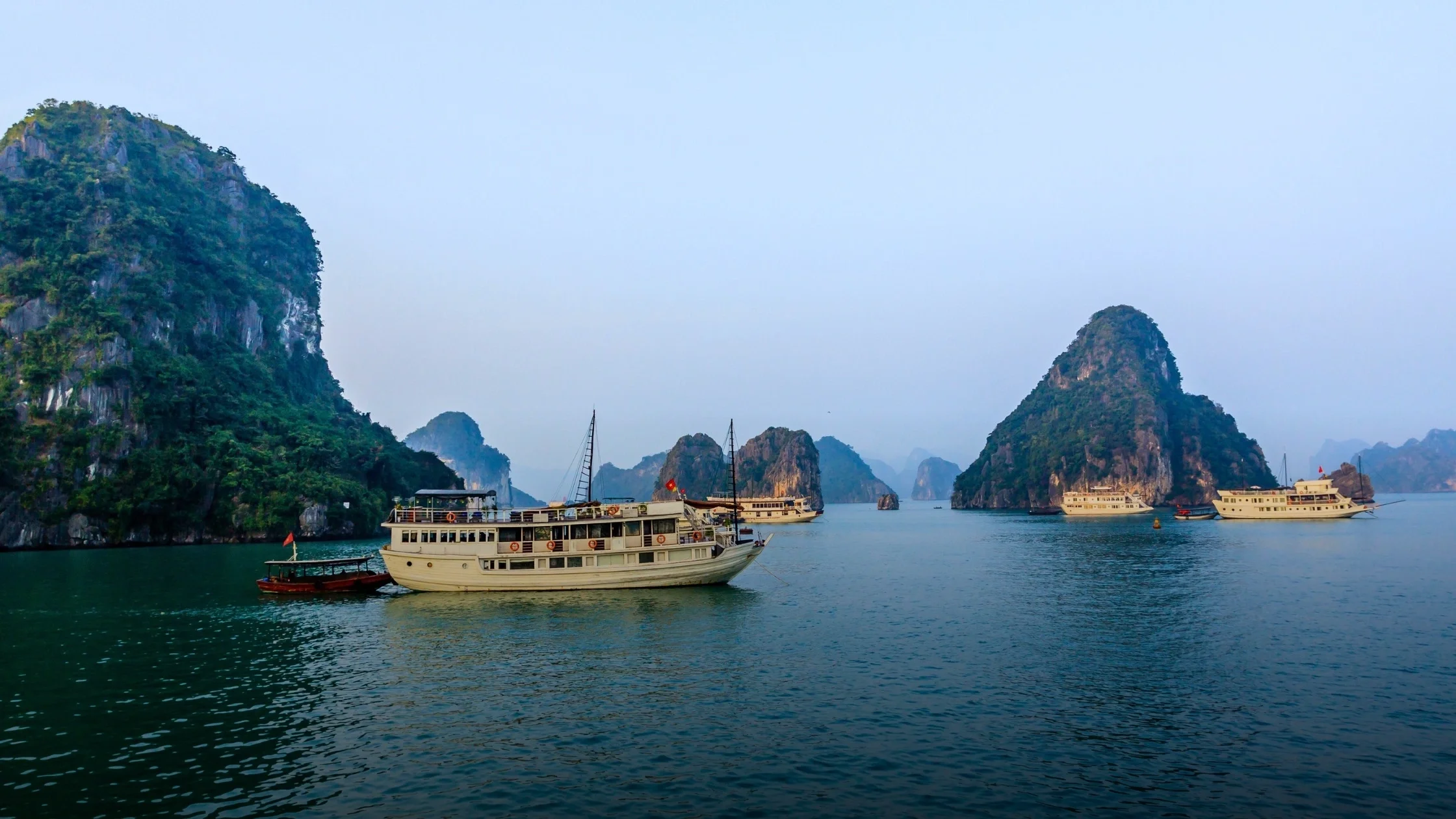 Boat crossing calm water between limestone islands in northern Vietnam