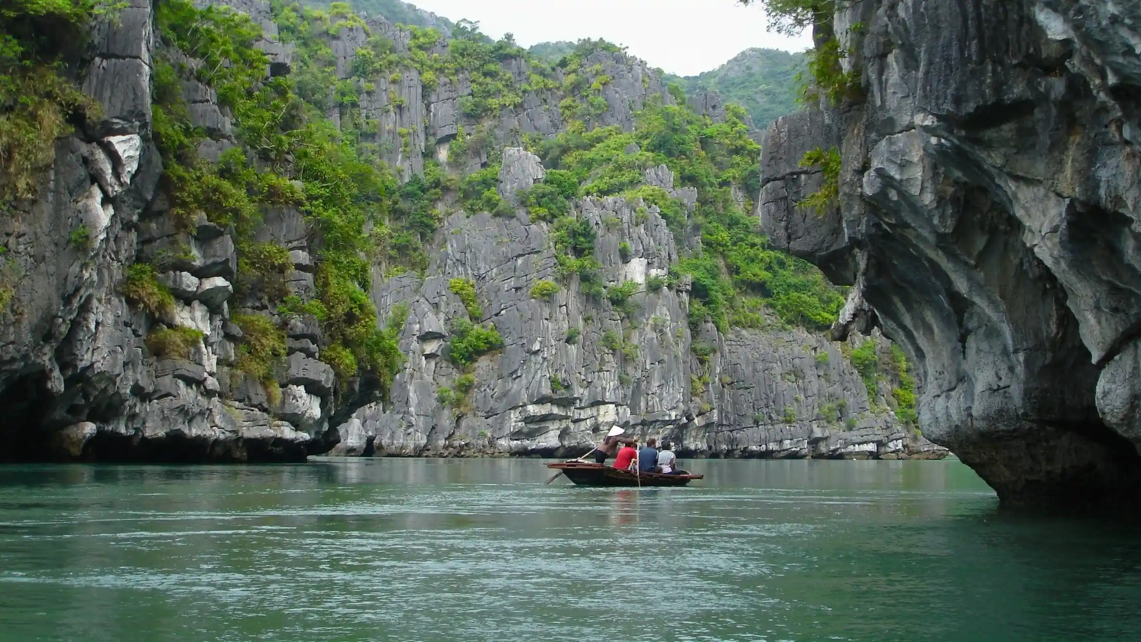 Cruise boat anchored in a sheltered bay among karst islands