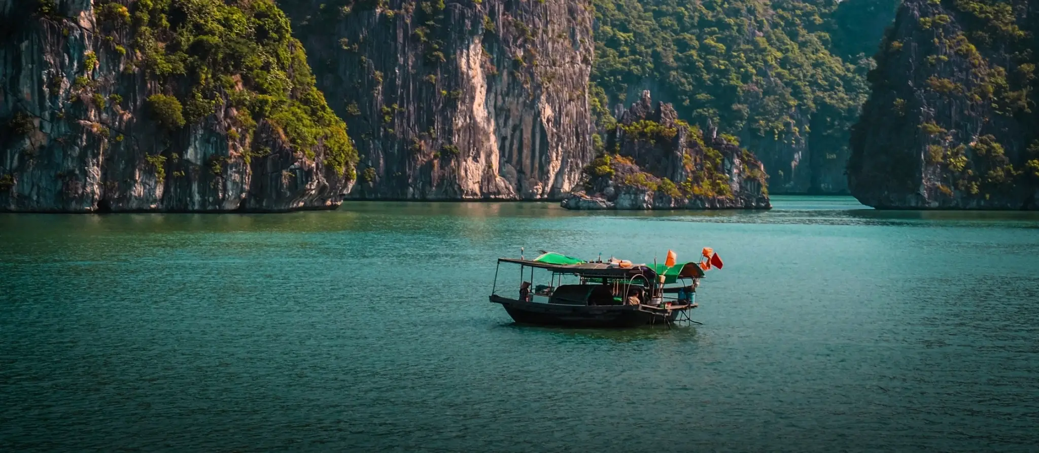 Wooden boat moored beside a limestone island in Ha Long Bay